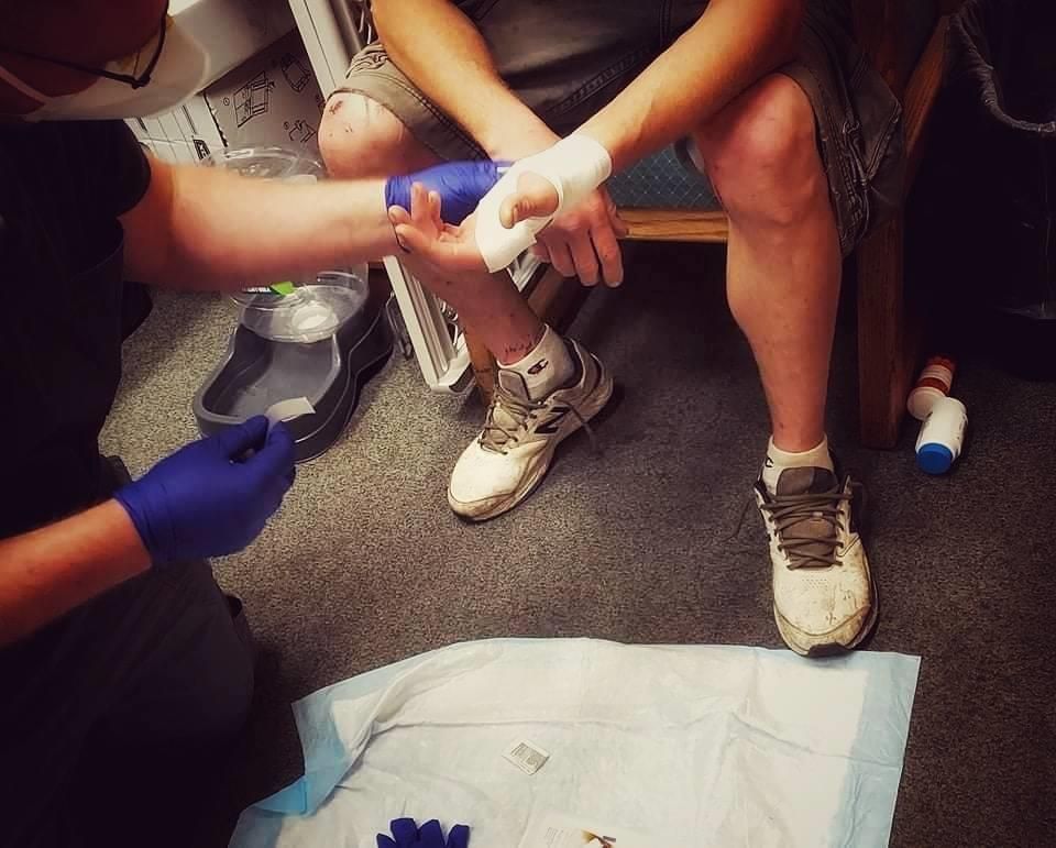 A clinic volunteer bandaging a patient's hand.